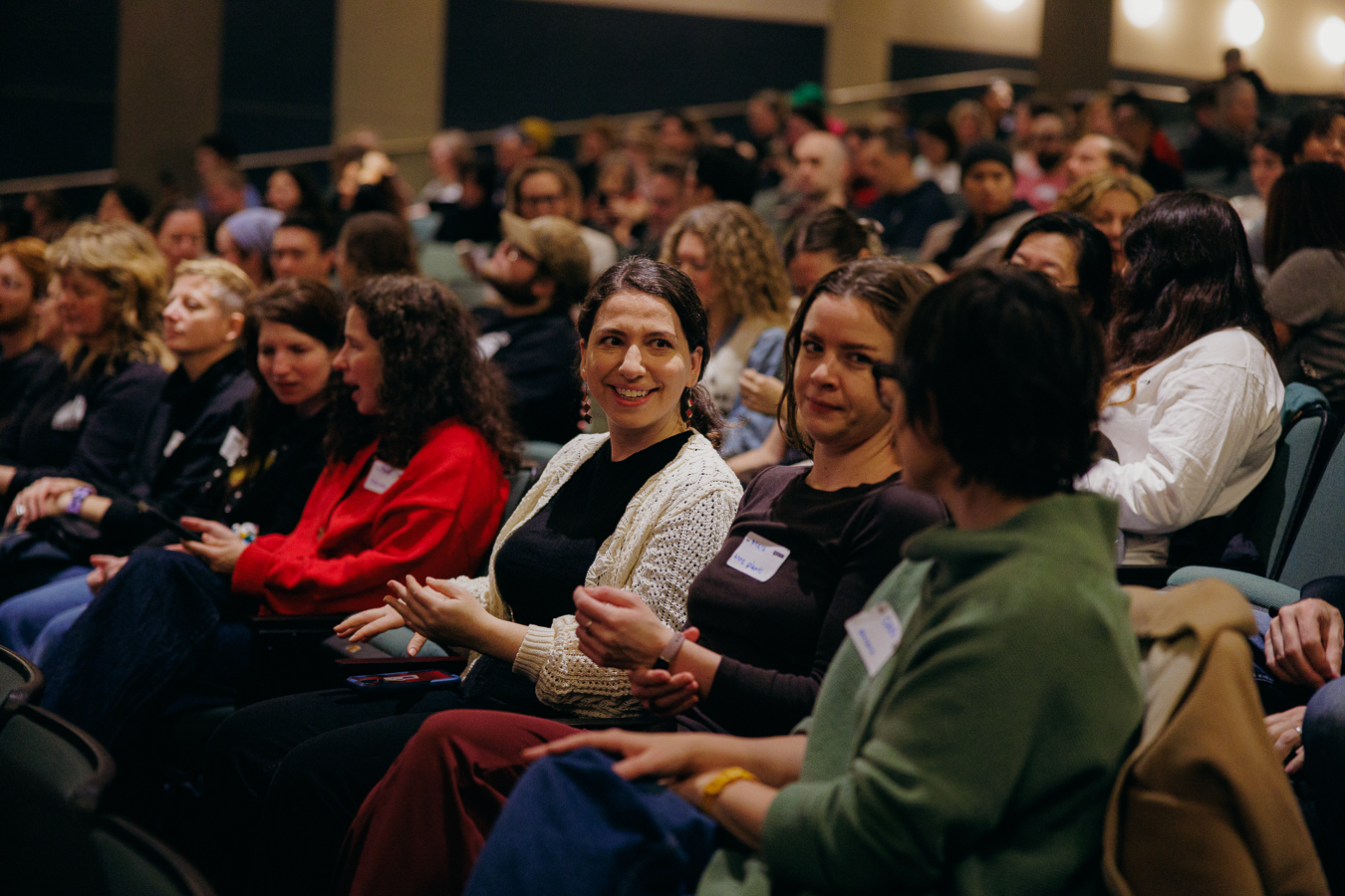 Photo of a crowd of smiling people sitting in the rows of a theater.