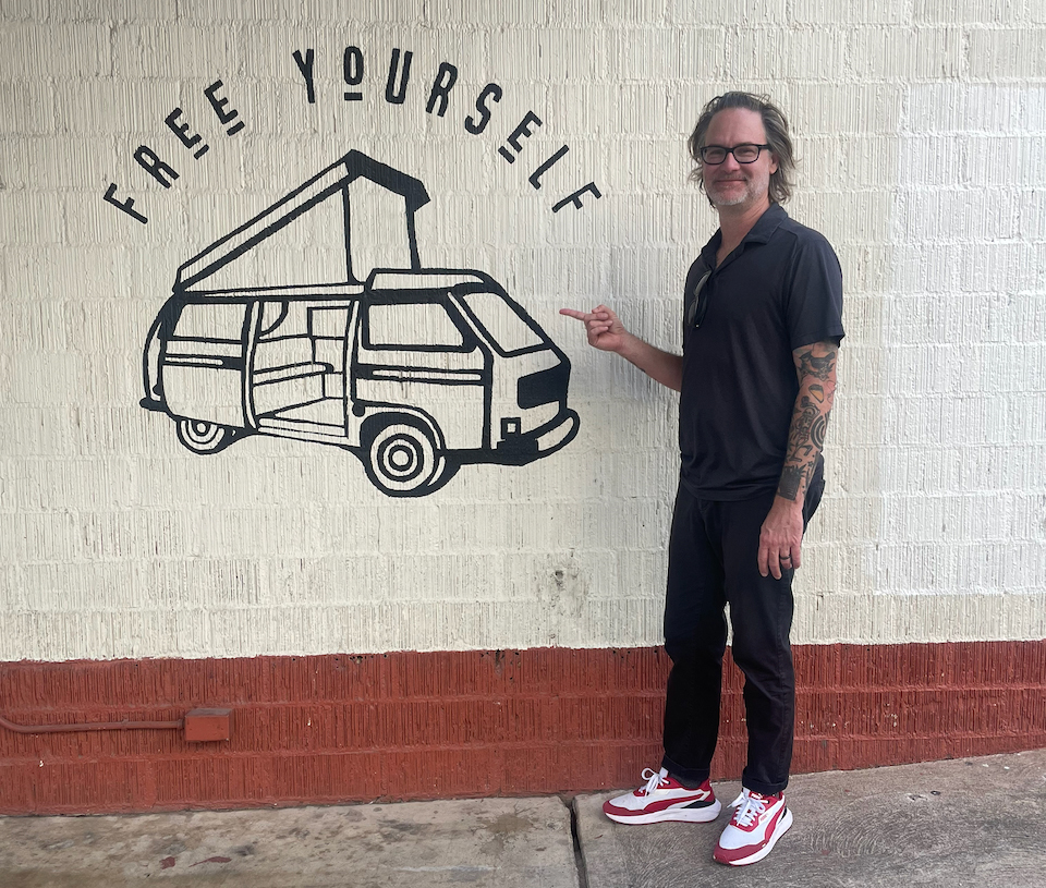 A man pointing to a mural that says free yourself