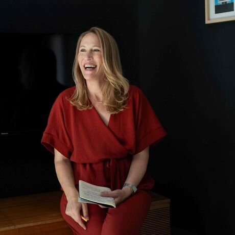 Indra sitzt schwarzer hintergrund rot sitzt lacht