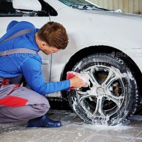 Man worker washing car s alloy rims on a car wash