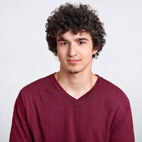 Headshot attractive curly youngster looks seriously camera