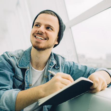 Guy sitting sofa writing notes smiling young down some 81413585